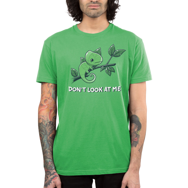 Premium Cotton T-shirt_Teeturtle Don't Look At Me Apple Green Featuring a little cartoon Chameleon trying to cloak itself against leaves while on a branch with 'Don't look at me.' written underneath the image.