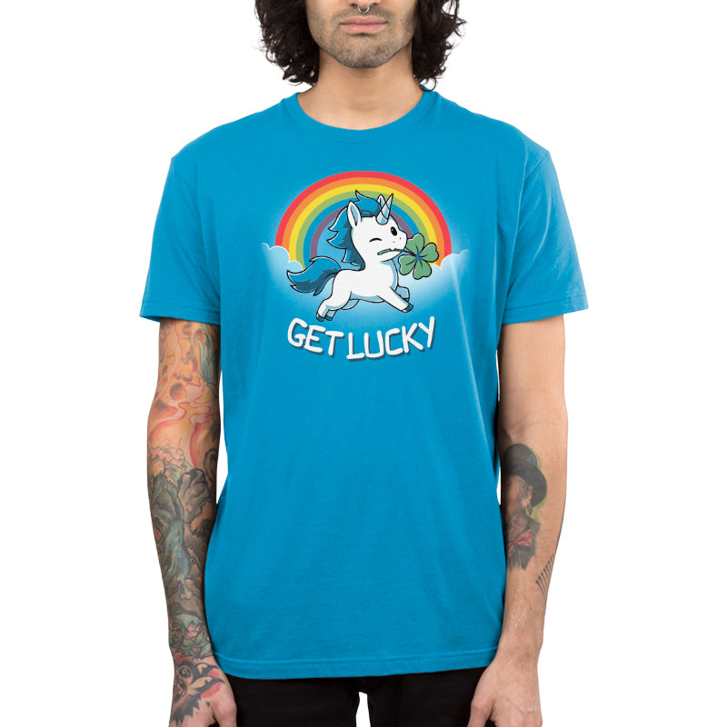 Premium Cotton T-shirt_Teeturtle Get Lucky cobalt blue t-shirt featuring a winking white unicorn holding a four-leaf clover while jumping through the clouds with a rainbow behind.
