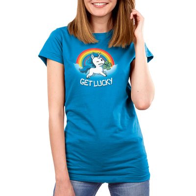 Premium Cotton T-shirt_Teeturtle cobalt blue Get Lucky apparel featuring a winking white unicorn holding a four-leaf clover while jumping through the clouds with a rainbow behind it. Caption reads, "get lucky".

