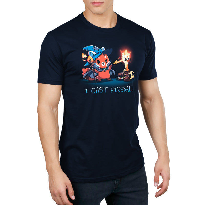 Person wearing a super soft, navy blue t-shirt featuring an illustration of a character in wizard attire casting a fireball, with the text "I CAST FIREBALL" underneath. The t-shirt is part of the I Cast Fireball collection by monsterdigital.