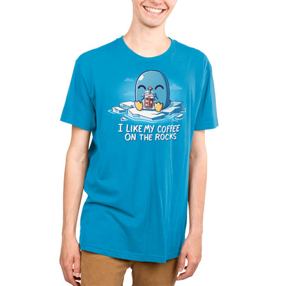 Person wearing a cobalt blue T-shirt with a cartoon penguin holding iced coffee and the text "I like my coffee on the rocks," showcasing the super soft ringspun cotton fabric of the I Like My Coffee on the Rocks by monsterdigital.