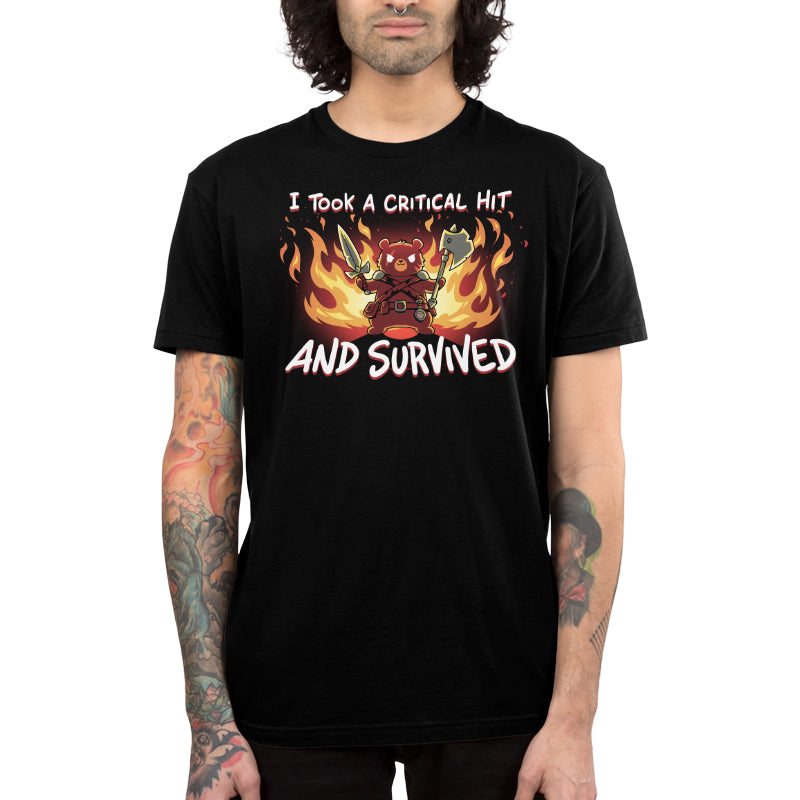 A person wearing a super soft ringspun cotton black t-shirt from monsterdigital with the text "I Took A Critical Hit And Survived" and a graphic of a warrior bear holding weapons in front of flames.