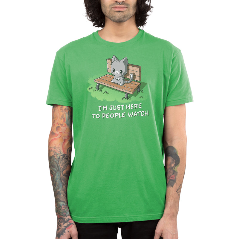 Premium Cotton T-shirt - Person wearing an apple green apparel with a cartoon cat sitting on a bench and the text "I'M JUST HERE TO PEOPLE WATCH." The super soft ringspun cotton makes the I'm Just Here to People Watch by monsterdigital incredibly comfortable.