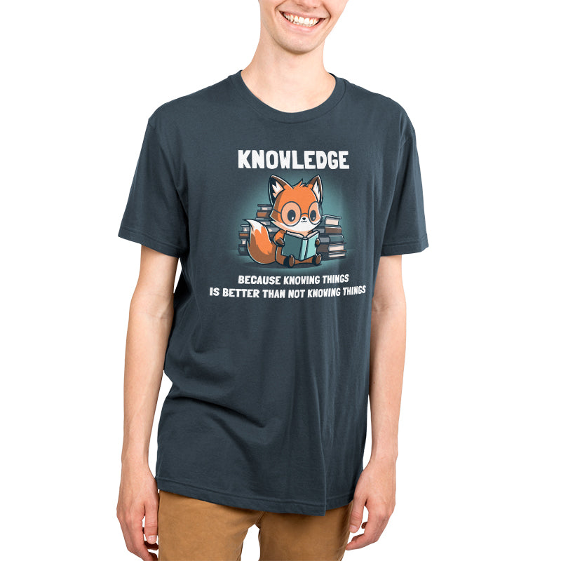 Premium Cotton T-shirt - A person wearing a super soft, denim blue Knowing Things by monsterdigital apparel with a fox reading books illustration and the text "KNOWLEDGE Because knowing things is better than not knowing things.