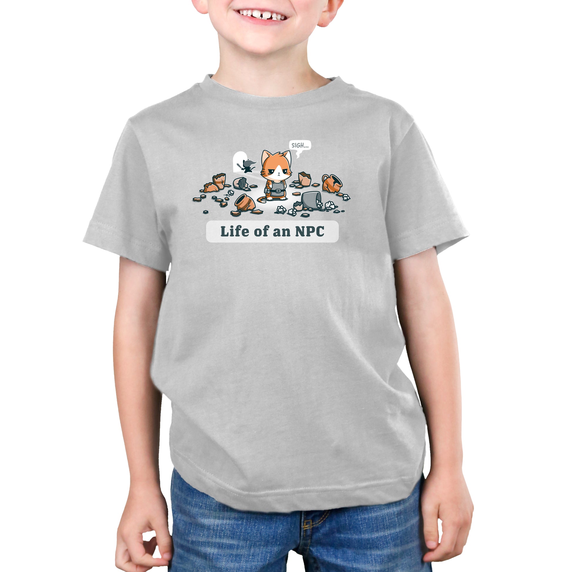 A child wearing a monsterdigital "Life Of An NPC" super soft ringspun cotton silver t-shirt with an illustration of a cat sitting among items, saying "Sigh," and the text "Life of an NPC" below the image.