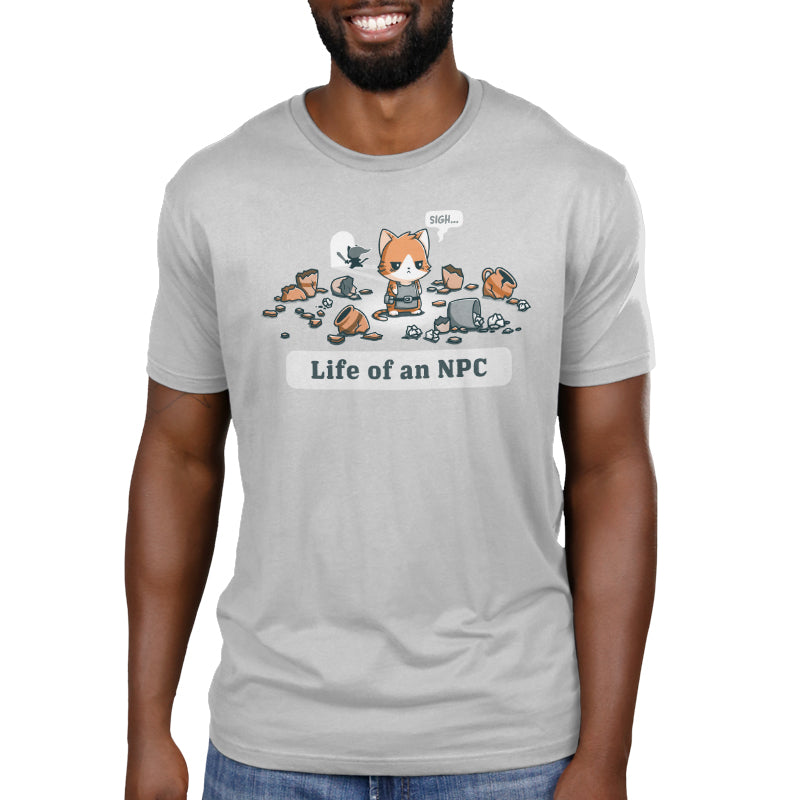 A man wearing a silver monsterdigital Life Of An NPC T-shirt made from super soft ringspun cotton, featuring a cartoon character surrounded by broken items and the text "Life of an NPC.
