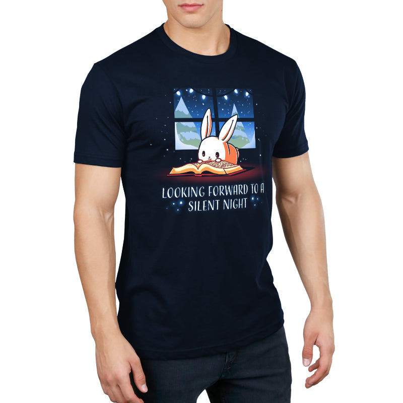 A person wearing a super soft ringspun cotton navy blue monsterdigital T-shirt featuring a cartoon bunny peeking from a window next to a book, with the text "Looking Forward to a Silent Night". This unisex tee promises both comfort and style.
