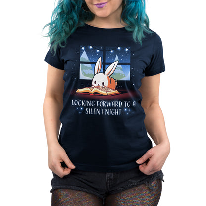 A person with blue hair is wearing a navy blue t-shirt featuring a rabbit reading a book by a window, with the text "Looking forward to a silent night." The unisex tee, named **Looking Forward to a Silent Night** by **monsterdigital**, is made from super soft ringspun cotton.