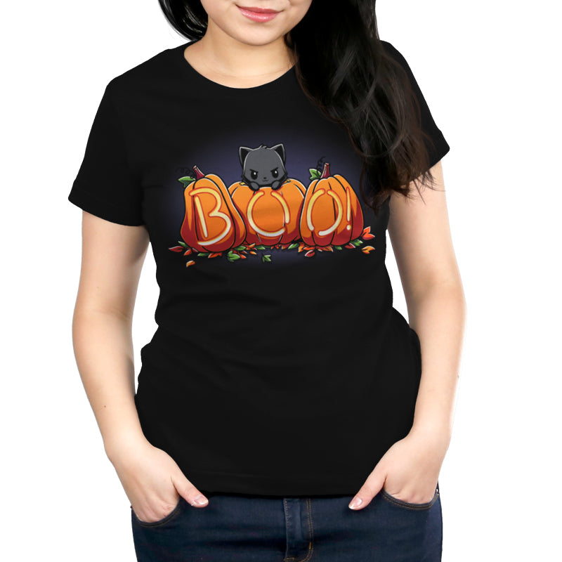 A person with long dark hair is wearing a super soft ringspun cotton T-shirt from monsterdigital featuring the Pumpkin Kitty design of a cat peeking over the word "BOO" formed by pumpkins.