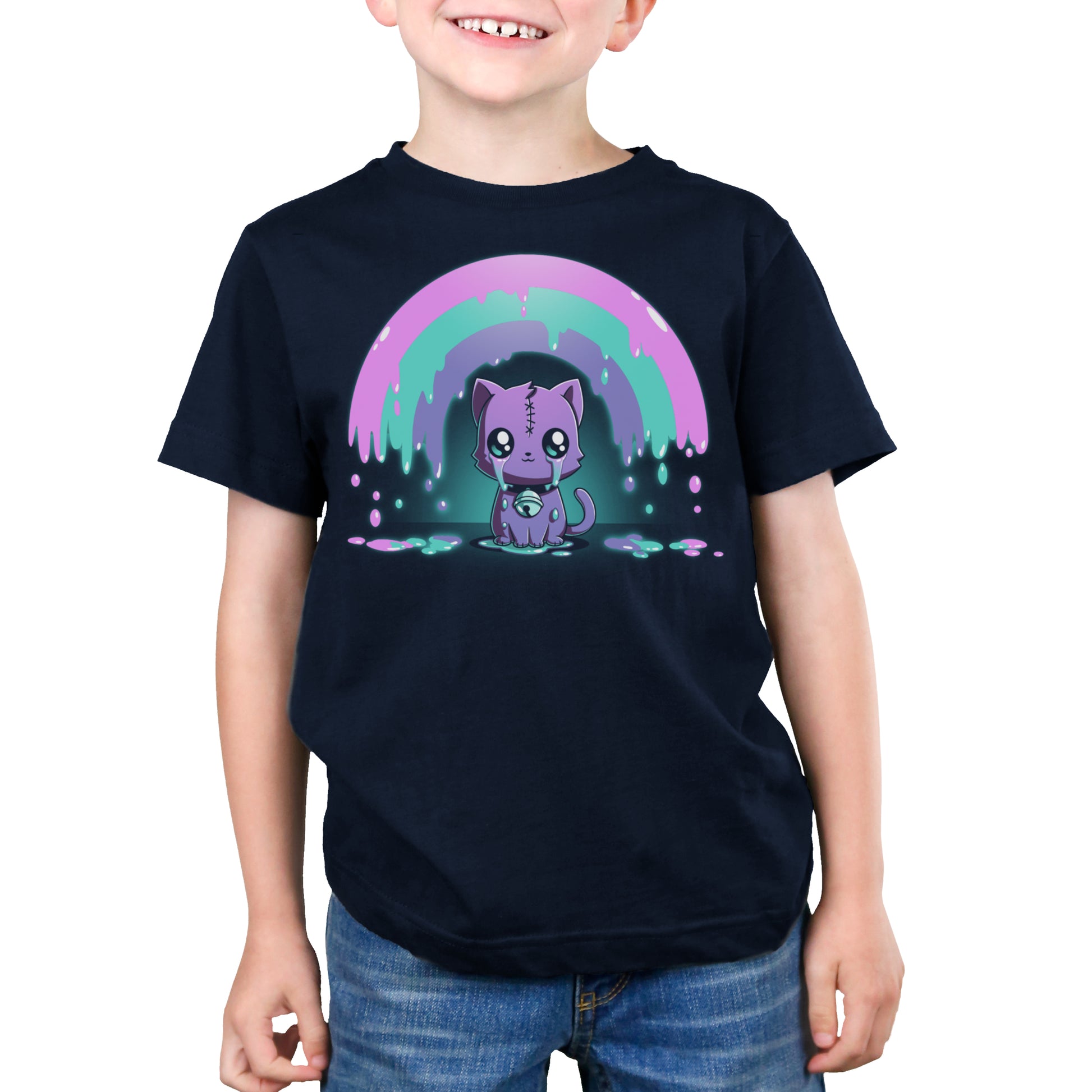 A child is wearing a navy blue, super soft cotton t-shirt with a cute, cartoonish purple cat under a pink and green dripping rainbow design on the front. The Rainbow Crying Cat tee by monsterdigital has the child smiling and their hands by their sides.