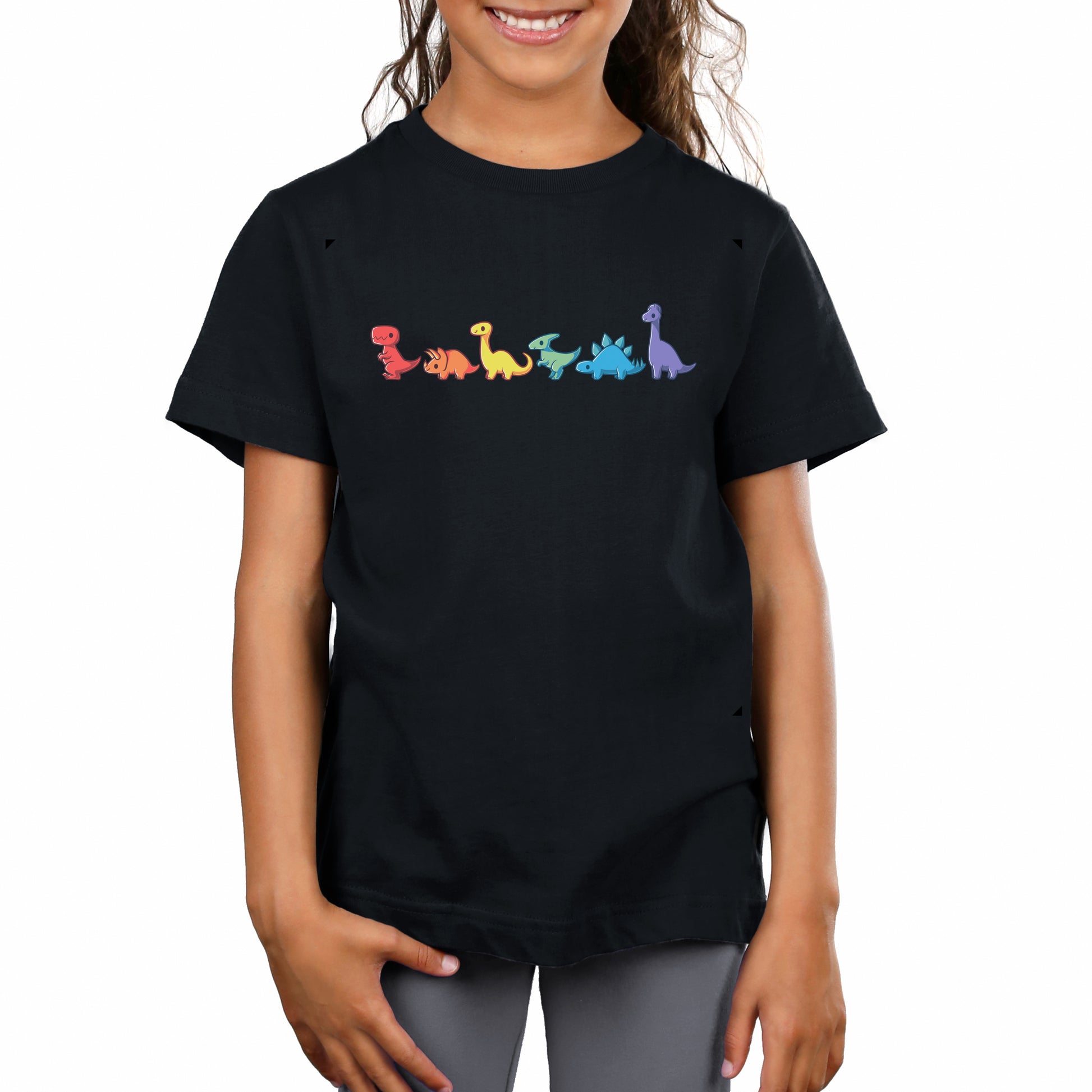 A child wears a black 100% super soft ringspun cotton Rainbow Dinos T-shirt by monsterdigital with small, colorful dinosaur graphics in a horizontal line across the chest.