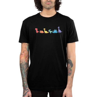 A person wearing a black, 100% super soft ringspun cotton T-shirt from monsterdigital featuring colorful dinosaur graphics arranged in a line. The unisex tee showcases the vibrant Rainbow Dinos design, and the individual has tattoos on their arms.