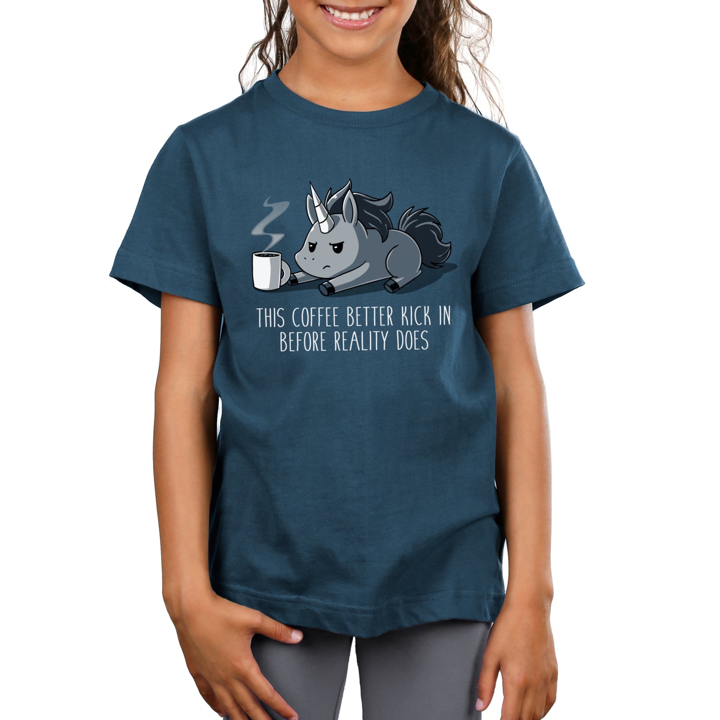 Premium Cotton T-shirt_Teeturtle denim blue Before Reality Kicks In apparel featuring a grumpy-looking unicorn on its stomach with a cup of steaming coffee in front of it. Caption reads 'This coffee better kick in before reality does".