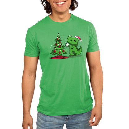 Premium Cotton T-shirt - Person wearing an Apple Green monsterdigital Christmas T-Rex apparel made of super soft ringspun cotton, featuring a cartoon dinosaur in a Santa hat, pointing at a small decorated Christmas tree.