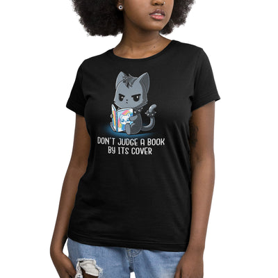 Premium Cotton T-shirt_TeeTurtle black Don't Judge a Book By It's Cover featuring seemingly grumpy, goth-looking cat wearing a spiked collar and spiked ring on its tail reading a bright, happy-looking rainbow-covered book above the text 'Don't Judge A Book By Its Cover'.
