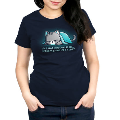 A person wearing a navy blue, super soft ringspun cotton unisex tee featuring a cartoon cat under a blanket with the text "I'VE HAD ENOUGH SOCIAL INTERACTIONS FOR TODAY." They have dark hair and hands in their front pockets. The tee is the Enough Social Interactions by monsterdigital.