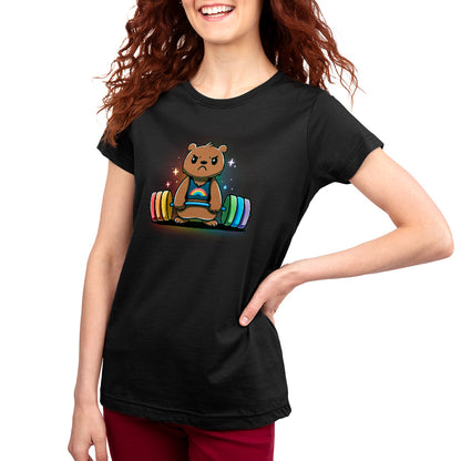 A person with long red hair wears a super soft ringspun cotton monsterdigital Gym Bear T-shirt featuring a cartoon bear lifting a colorful barbell, standing with one hand on their hip and smiling.
