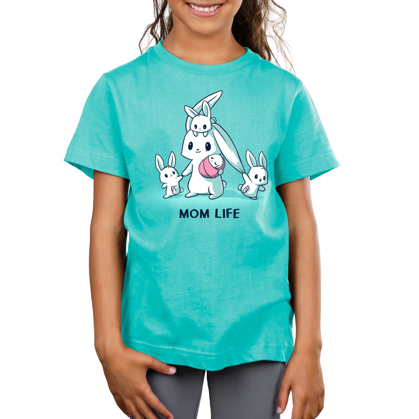 A child is shown from the waist up wearing a Caribbean Blue monsterdigital t-shirt with a cartoon of a mother rabbit carrying a baby rabbit, flanked by two smaller rabbits. The text "MOM LIFE" is below the illustration.