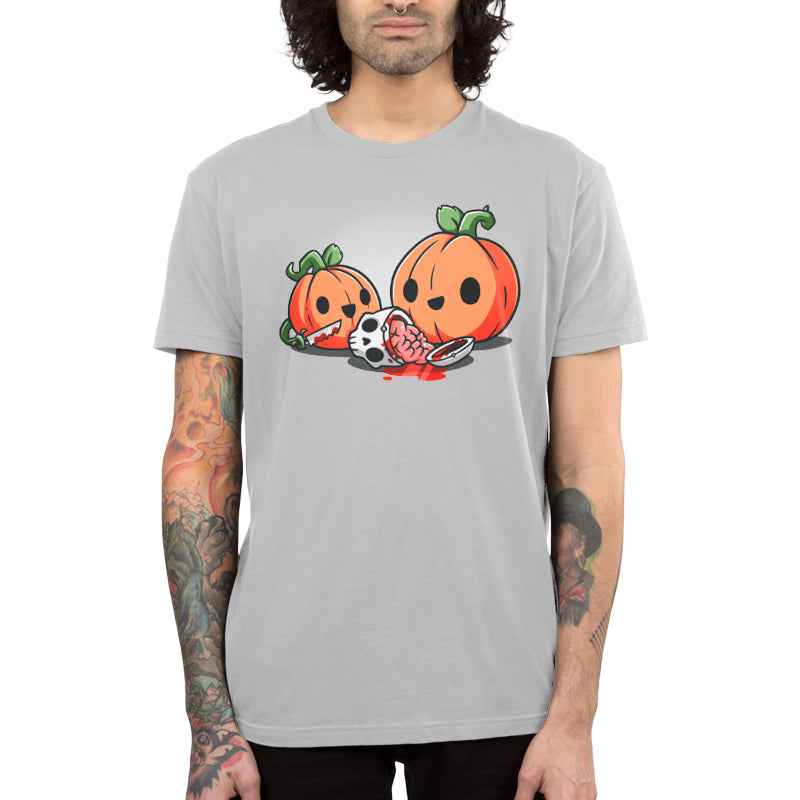 Person wearing a super soft ringspun cotton gray monsterdigital T-shirt featuring two cartoon pumpkins with smiling faces, one holding a knife, and a severed limb with a paw and blood in front of them. The person has tattoos on both arms. It's the perfect Pumpkin Carving T-shirt for true crime documentary enthusiasts.
