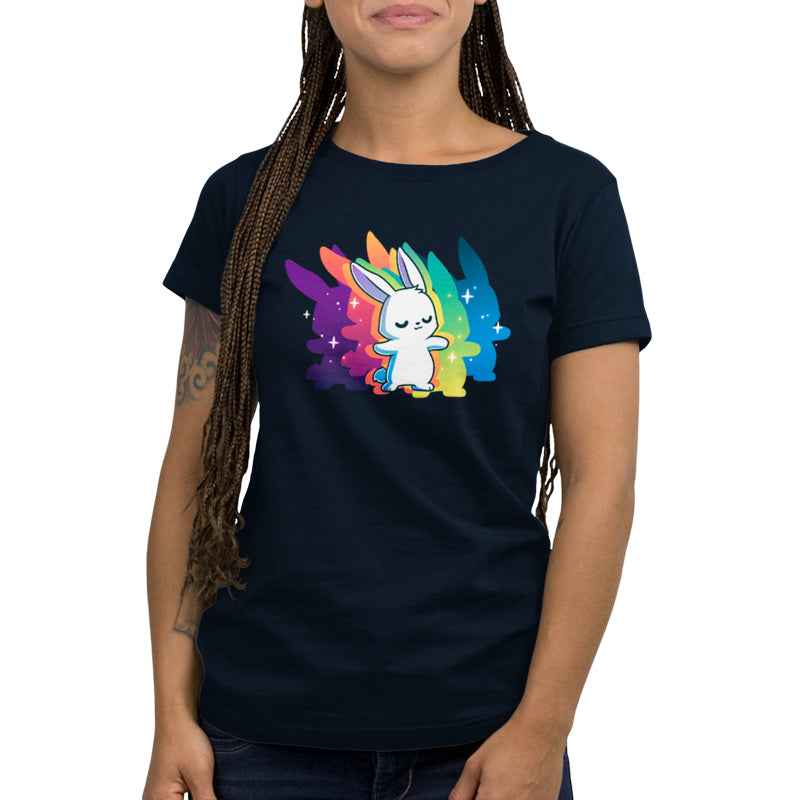 A person is wearing a super soft ringspun cotton navy blue T-shirt featuring a cute white bunny with rainbow-colored wings and stars in the background from monsterdigital's "Queer Vibes Only" collection. The person has long braided hair and a tattoo on their left arm.