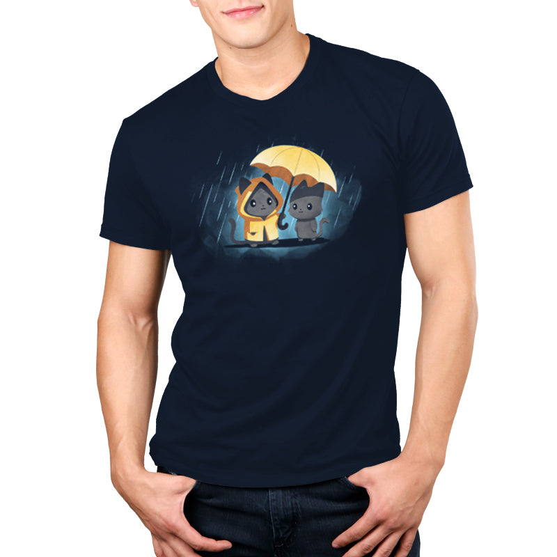 A person wears a navy blue unisex tee made from 100% super soft ringspun cotton, featuring two cartoon dogs, one in a yellow raincoat, sharing a yellow umbrella in the rain. This tee is named Sharing Kindness and is by monsterdigital.