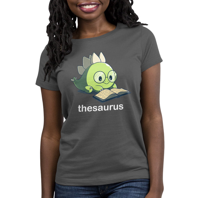 Premium Cotton T-shirt - A person wearing a charcoal gray apparel featuring a cartoon dinosaur reading a book with the word "Thesaurus" printed below the illustration from monsterdigital is smiling.