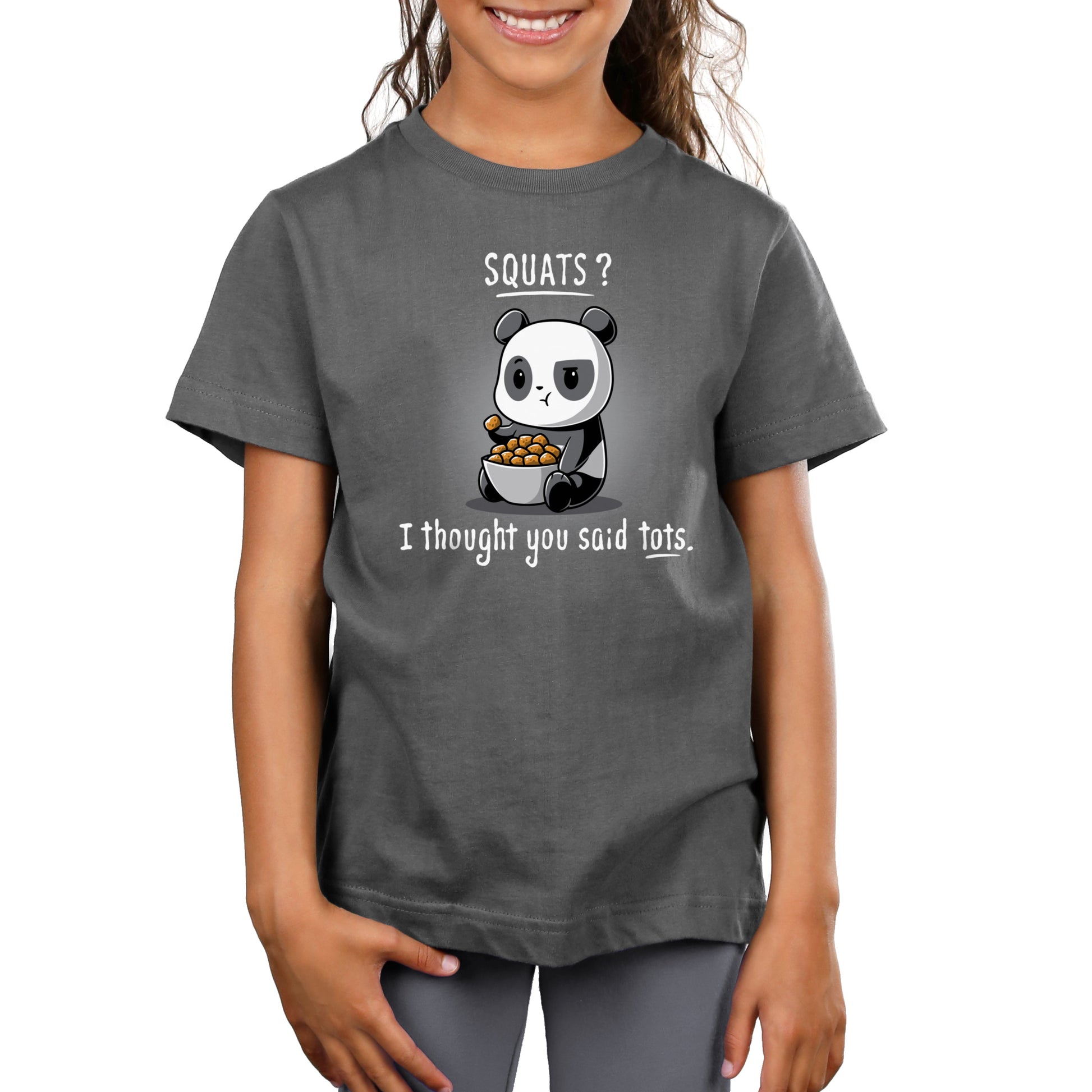A girl wears a charcoal gray T-shirt featuring a cartoon panda holding tater tots with the text "Tots > Squats" by monsterdigital.