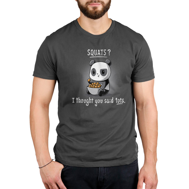 A man wearing a charcoal gray t-shirt featuring a cartoon panda holding a bowl of tater tots with the text "Tots > Squats" by monsterdigital.
