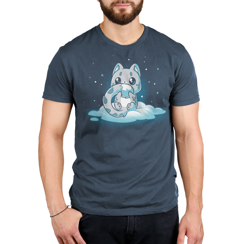 Premium Cotton T-shirt - A person wearing a denim blue apparel with a graphic of a sleeping cat curled up on a cloud, surrounded by stars. The super soft ringspun cotton Snuggly Snow Leopard from monsterdigital promises ultimate comfort, making it feel like you're wrapped in the snuggly embrace of a snow leopard.