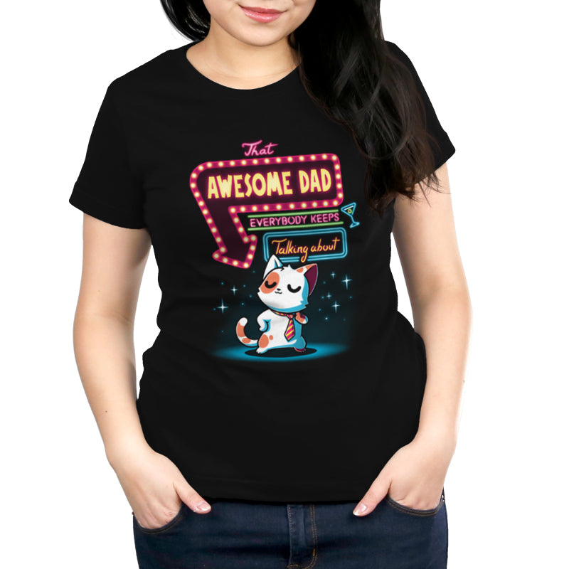 A person wearing a black T-shirt made of Super Soft Ringspun Cotton, featuring a cartoon cat and text that reads "That Awesome Dad Everybody Keeps Talking About" from monsterdigital.