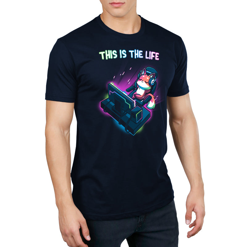 A person wearing a navy blue monsterdigital t-shirt with a colorful graphic of a character using a gaming console and the text "This Is the Life.