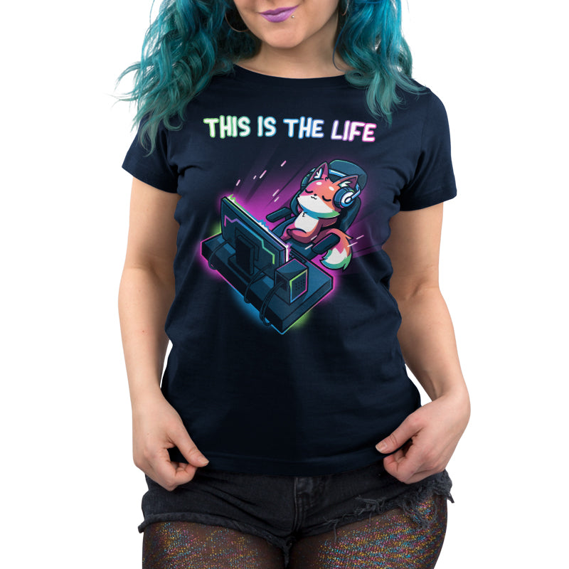 Person wearing a navy blue monsterdigital t-shirt with an illustration of a fox wearing headphones and playing a video game, accompanied by the text "THIS IS THE LIFE.
