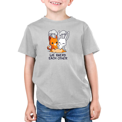 Premium Cotton T-shirt - A young child wearing a gray apparelfrom the monsterdigital collection with an illustration of a cat and bunny dressed as bakers kneading dough, accompanied by the text "We Knead Each Other." Made from super soft ringspun cotton, this "We Knead Each Other" apparel is as comfy as it is cute.