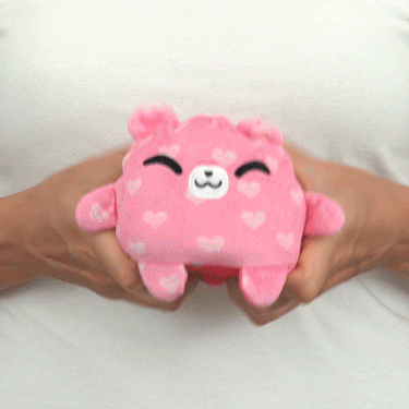 A TeeTurtle woman holding a pink TeeTurtle Reversible Bear Plushmate (Hearts) stuffed animal.