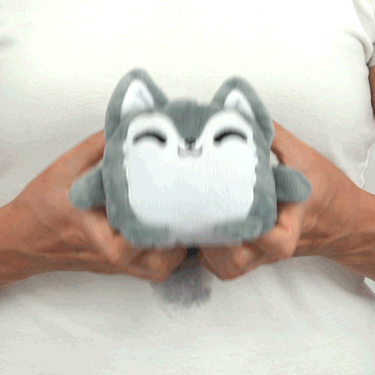 A person holding a TeeTurtle Reversible Wolf Plushmate plush toy.