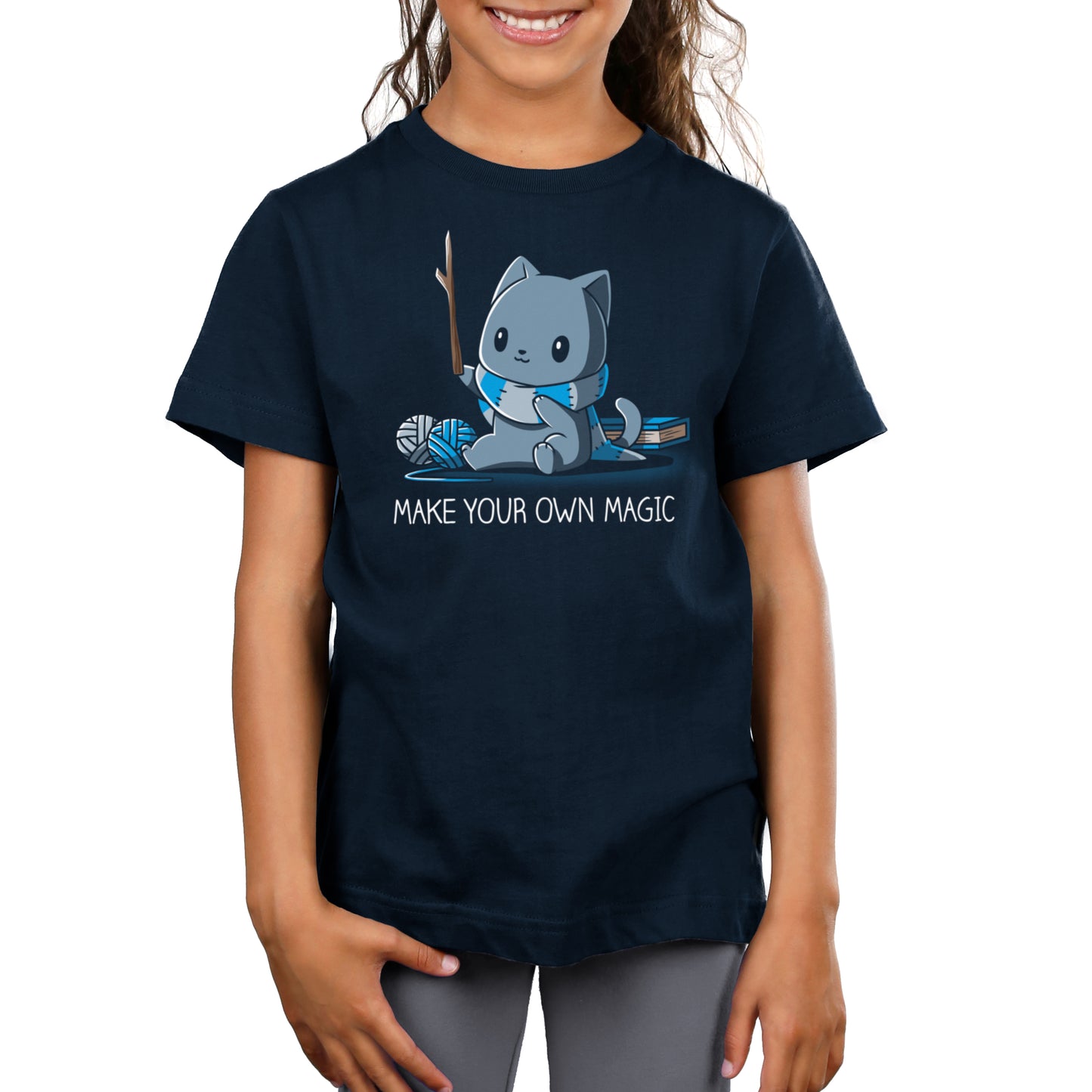 Premium Cotton T-shirt_Teeturtle Make Your Own Magic Navy Blue Featuring a gray cat sitting in front of a book next to yarn with a wand-like stick and a crafted scarf with the text 'Make Your Own Magic' below.