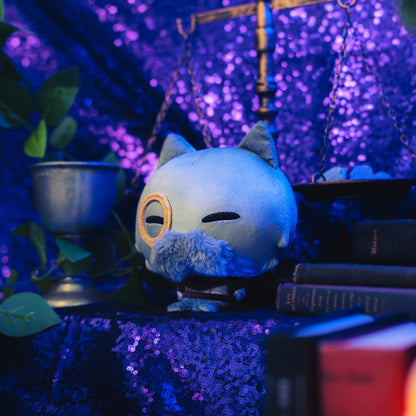 Cloudheads: 5" Mystic Moon (Galileo) - A plush gray cat with pointed ears, a fuzzy gray mustache, and a monocle over one eye, shown with a sparkly purple backdrop as well as a leafy green plant and a pile of books. 