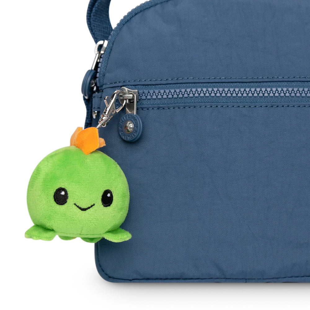 A portable TeeTurtle blue purse with a TeeTurtle Stego Plushie Charm Keychain hanging from it.