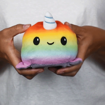 A person holding an adorable TeeTurtle Reversible Shark & Narwhal Plushie (Gray + Rainbow).
