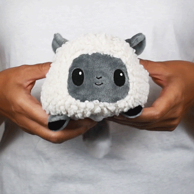 A person cuddling a TeeTurtle Reversible Wolf & Sheep Plushie stuffed animal from TeeTurtle.