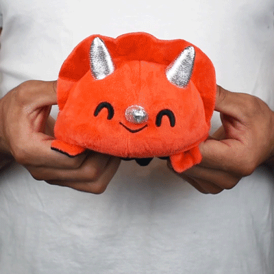 A person holding a TeeTurtle Reversible Triceratops Plushie (Skeleton).