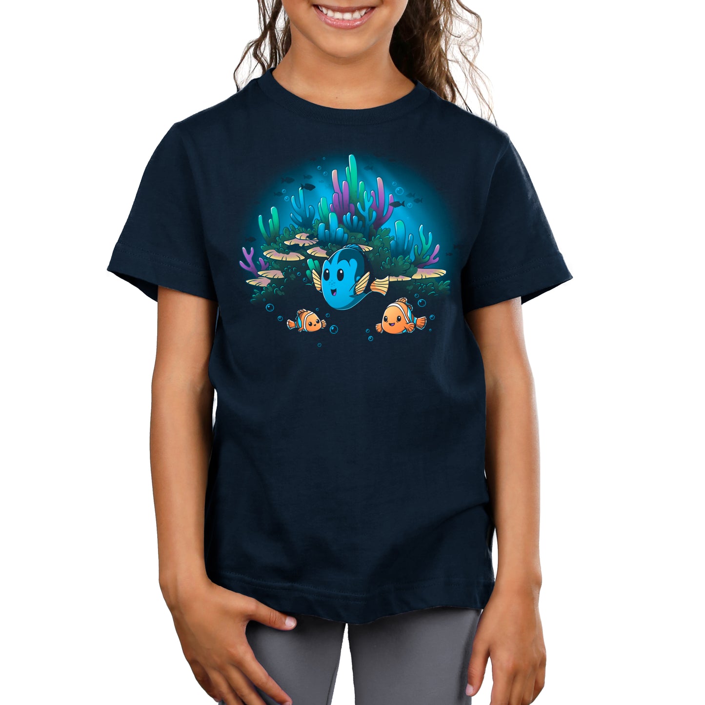 A girl wearing a navy t-shirt with an image of Nemo, from Pixar's Finding Nemo, in the ocean.