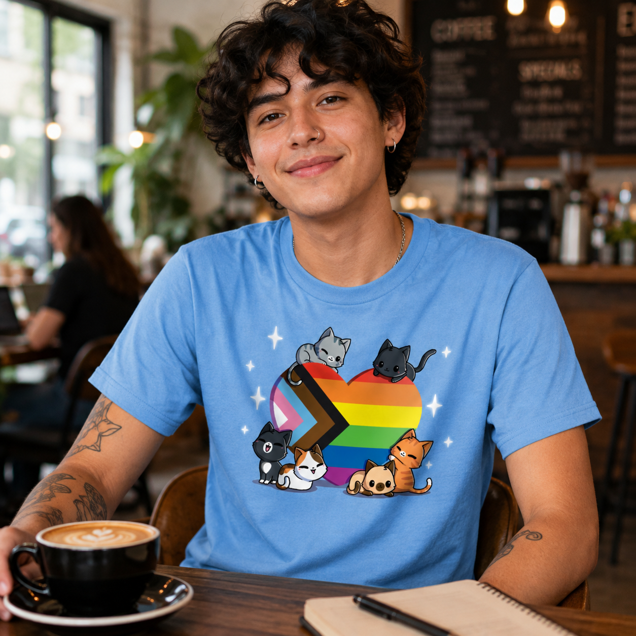 Premium Cotton T-shirt_TeeTurtle light blue Progress Purride Premium Cotton T-shirt featuring six different cats on or around a heart that is the colors of the progress pride flag. There are sparkles around them and all the cats look happy. 