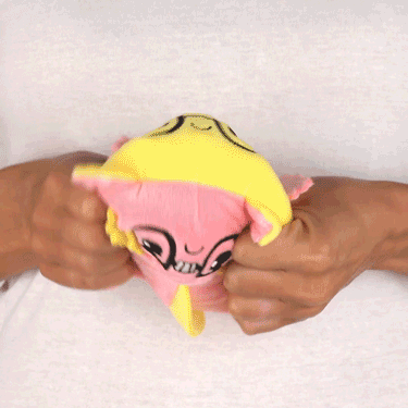 A person holding a TeeTurtle Reversible Axolotl Plushie (Glasses).