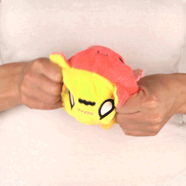 A woman holding a TeeTurtle Reversible Axolotl Plushie (Yellow + Red) toy.