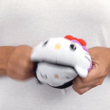 A woman holding a Sanrio TeeTurtle Reversible Hello Kitty Plushie (Bat + Witch) toy.