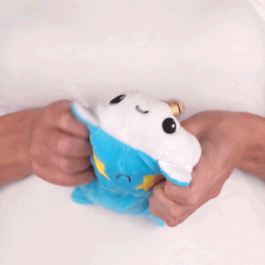A woman is joyfully holding a TeeTurtle Reversible Narwhal Plushie (Blue + White) in her hands.