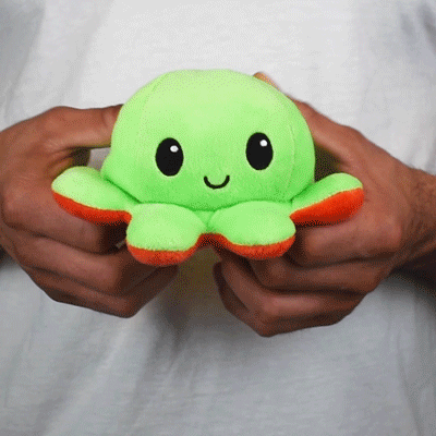 A person holding a TeeTurtle Reversible Octopus Plushie (Red + Green) from TeeTurtle.