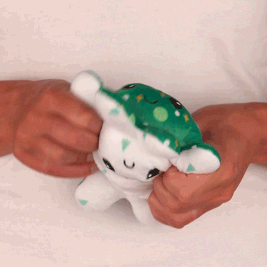 A person holding a TeeTurtle Reversible Octopus Plushie (Snowy Trees + Christmas Ornaments).