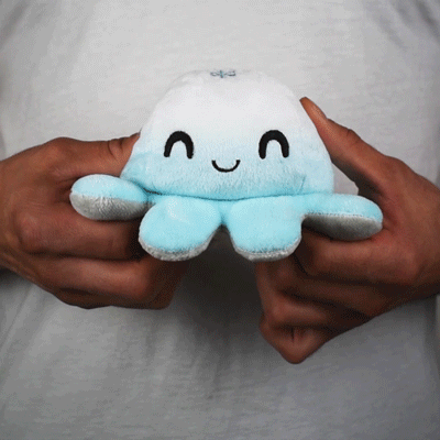 A person holding a blue TeeTurtle Reversible Octopus Plushie (Cloud + Snowflake).